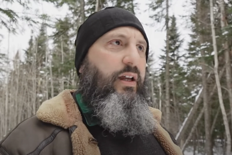 Bryan Denlinger outdoors in the woods in the snow, wearing a jacket and skull cap, disucssing "Remembering, Cleansing, & Perfecting"
